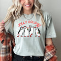Jolly Holiday Penguins Christmas Parade In Cozy Winter Village Scene With Snowflakes And Cheer Comfort Colors Tee